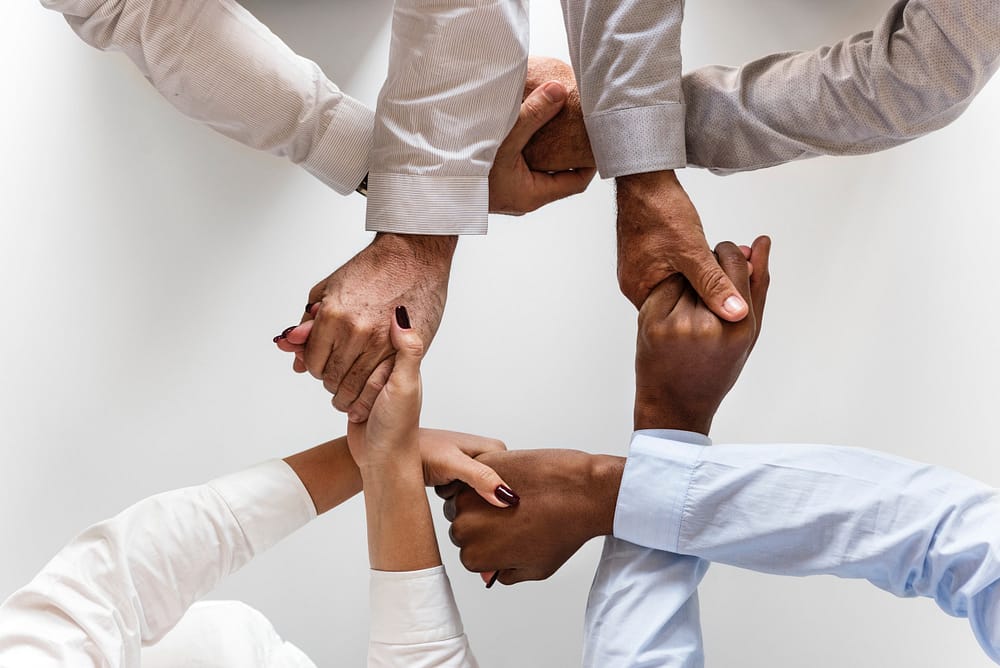 Close up of four people holding hands, building network